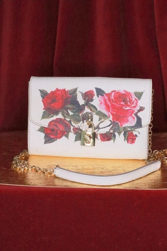 A white purse with red roses on it
