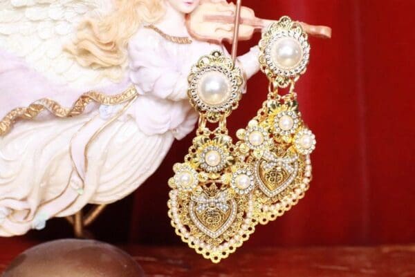 A pair of gold earrings with pearls hanging from the side.