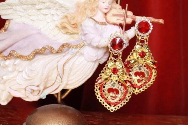 A pair of earrings with red and gold design.