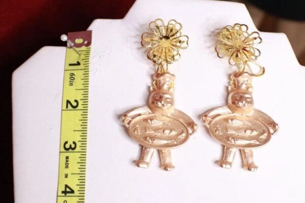 A pair of gold earrings sitting on top of a white board.