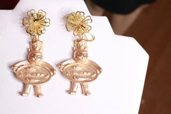 A pair of gold earrings with flowers hanging from them.