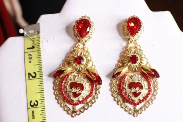 A pair of red and gold earrings on a white display.