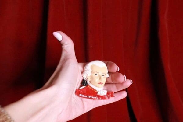 A person holding a small ceramic portrait of mozart.