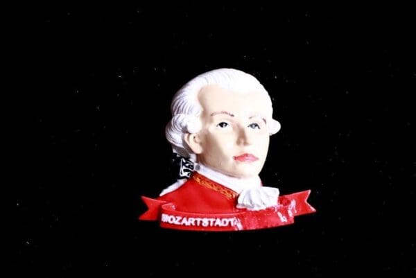 A bust of a man with white hair and red shirt.