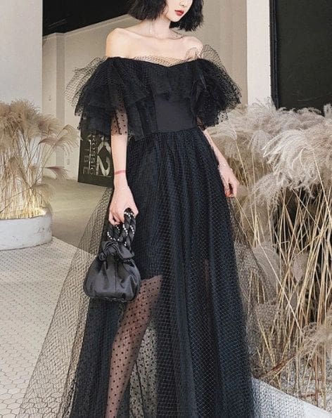 A woman in black dress holding onto a purse