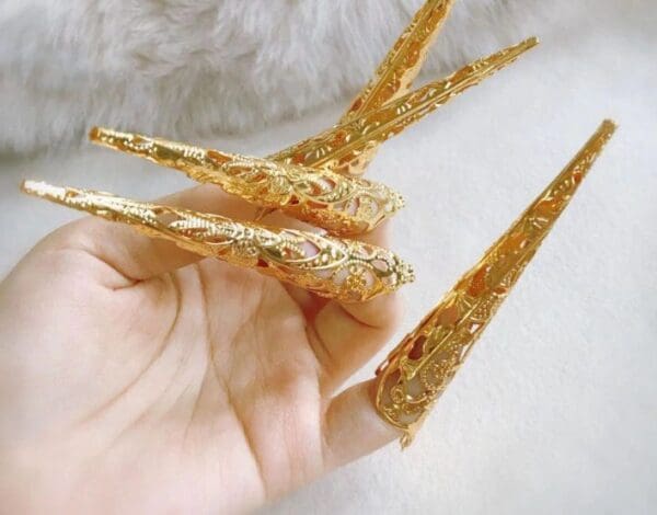 A person holding some gold spikes in their hand