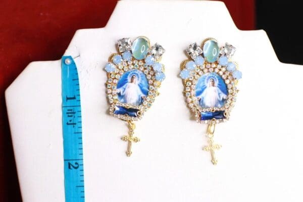 A pair of earrings with jesus and cross on them.