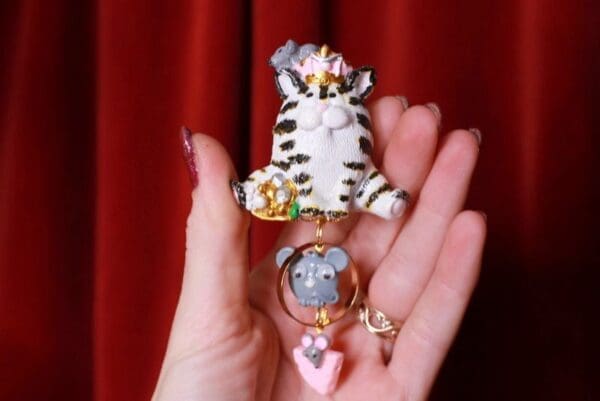 A hand holding two different keychains with cats on them.