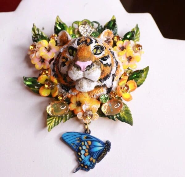 A tiger and butterfly brooch with flowers on it