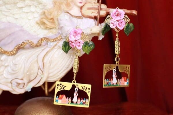 A pair of earrings with pink flowers and a picture frame.