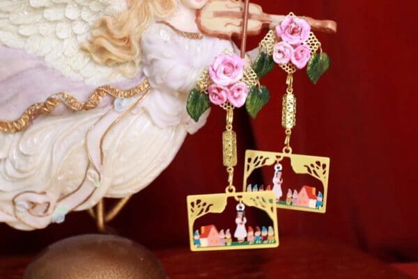 A pair of earrings with horses and flowers on them.