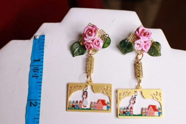 A pair of earrings with pink roses and gold chains.