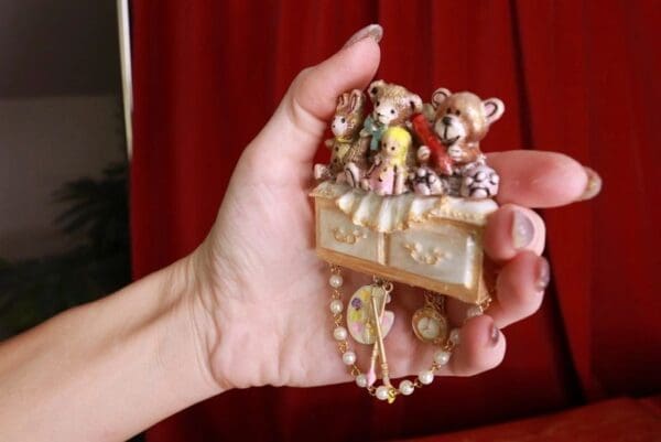 A hand holding a small necklace with various items.