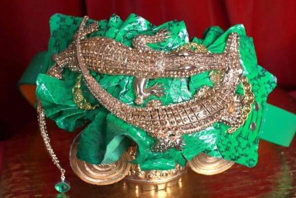 A close up of a green and gold alligator statue