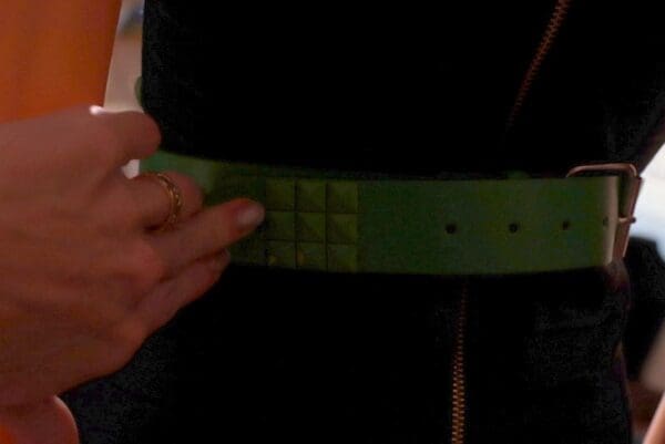A person wearing a green belt with squares on it.