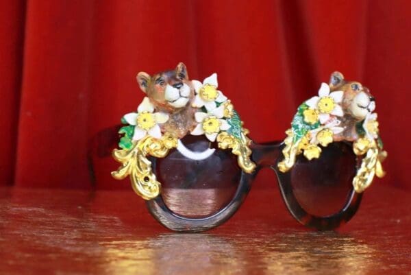 A pair of sunglasses with flowers and a cat on the side.