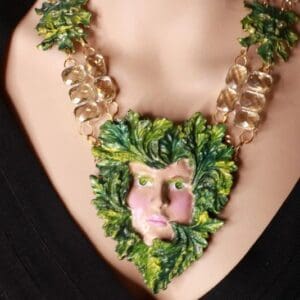 A woman wearing a necklace with leaves and a face.