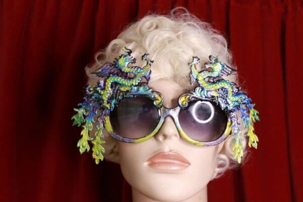 A mannequin wearing sunglasses with dragon decorations on them.