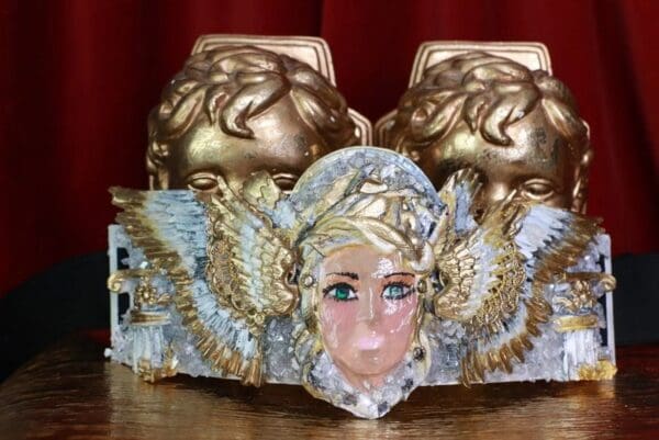 A close up of a statue head with gold decorations