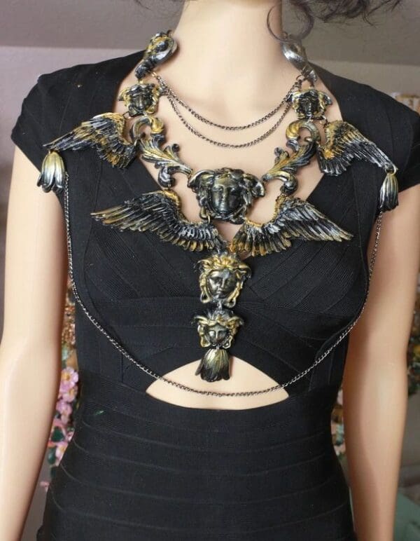 A woman wearing a black dress with chains around her neck.