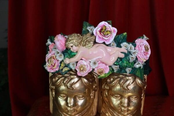 A pair of gold cups with pink flowers and a cherub on top.