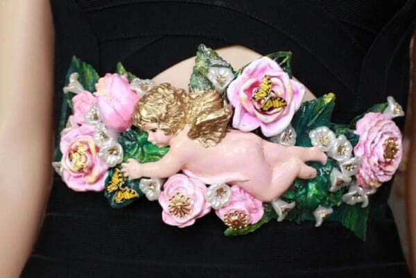 A pink angel with flowers on the side of it.
