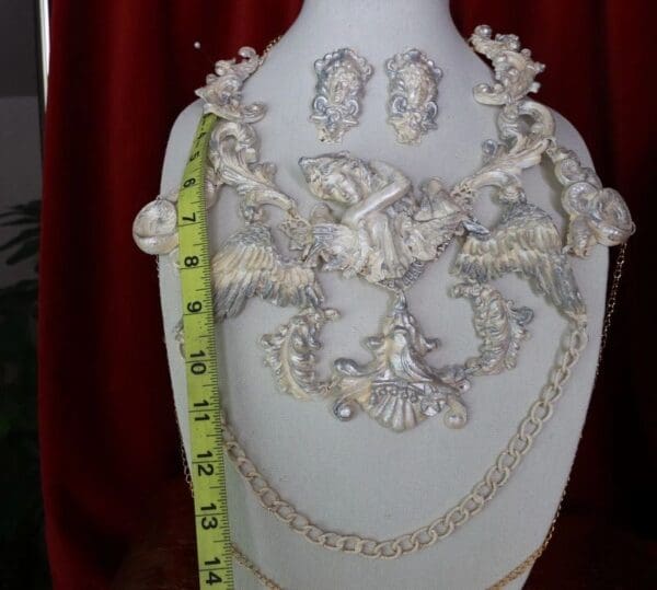 A white vase with a necklace and earrings on it