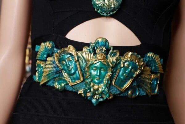 A close up of the face of a woman wearing a green and gold mask.