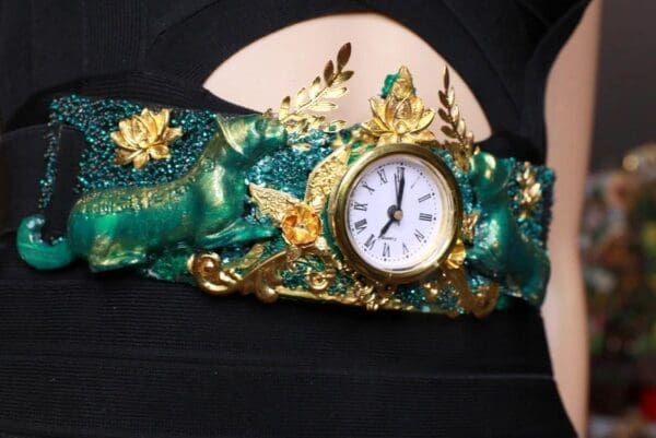 A woman wearing a green and gold bracelet with a clock.