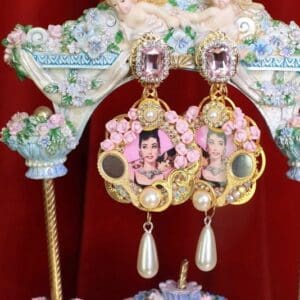 A pair of earrings with pink flowers and pearls.
