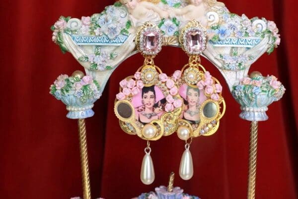 A pair of earrings with pink flowers and pearls.