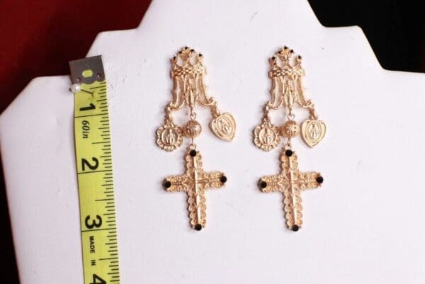 A pair of earrings with crosses and medals on them.