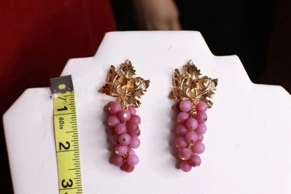 A pair of earrings with pink beads and gold leaves.