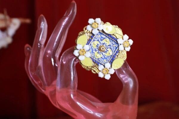 A hand holding something with a yellow and blue ring on it.
