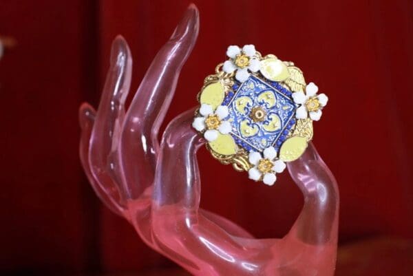 A hand holding something with a blue and yellow flower design on it.