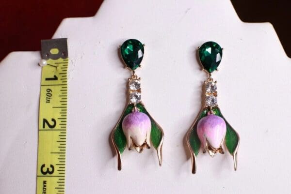 A pair of earrings with green and purple flowers.