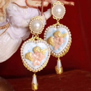 A pair of earrings with pearls and angels on them.