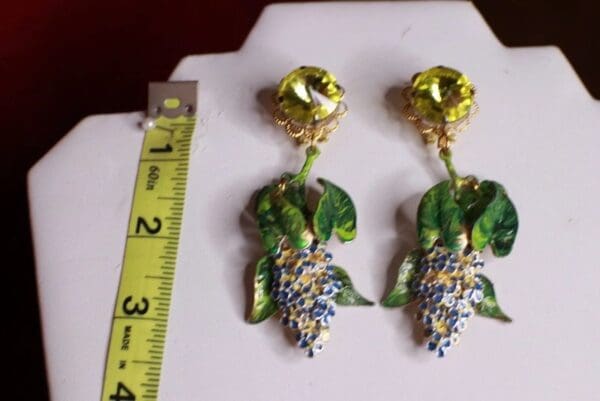 A pair of earrings with grapes and leaves on them.