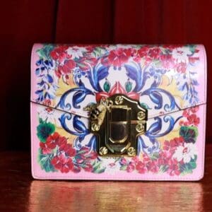 A pink purse with flowers on it sitting on top of a table.