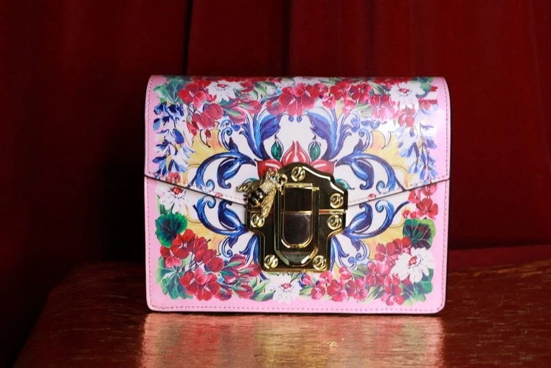 A pink purse with flowers on it sitting on top of a table.