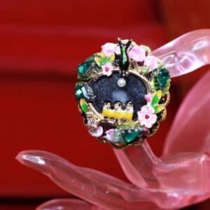 A close up of a ring on top of a pink flower.