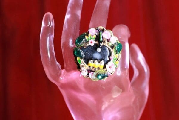 A hand holding a ring with a batman design on it.