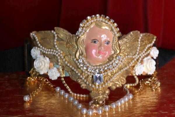 A gold angel with pearls and beads on top of it.
