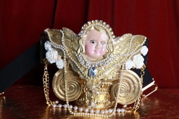 A gold statue with pearls and a face on it.