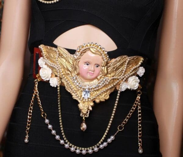 A woman wearing a black dress with gold accessories.