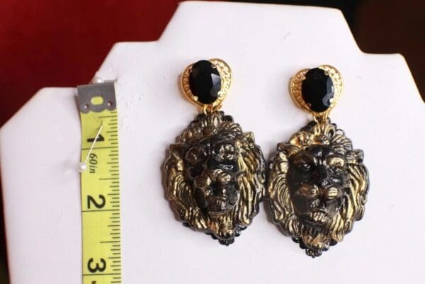 A pair of earrings with a lion head and black stone.