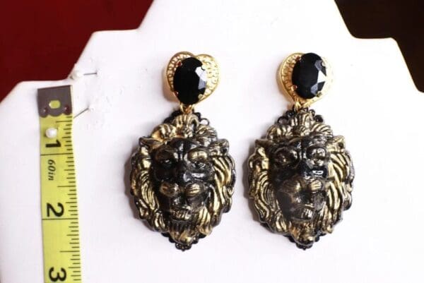 A pair of earrings with black and gold faces.