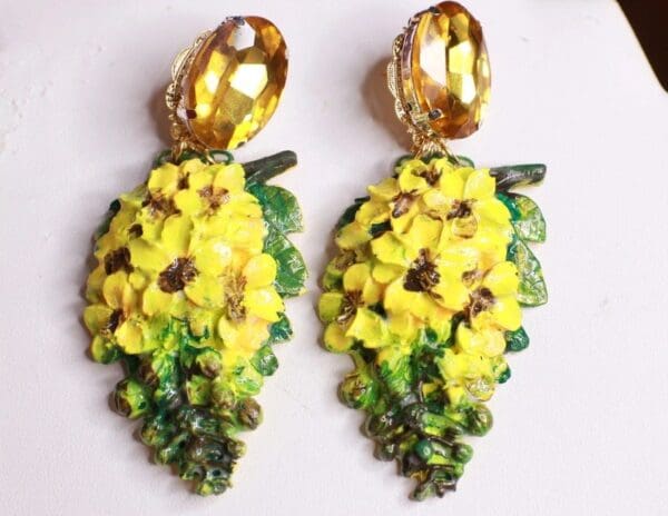 A pair of yellow and green earrings with gold accents.
