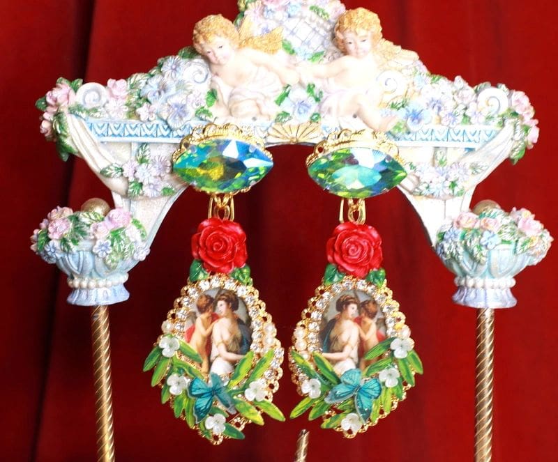 A pair of earrings with roses and pictures on them.