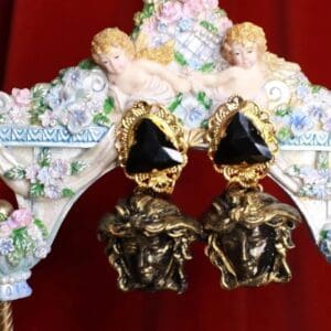 A pair of earrings with black stones and gold plated faces.